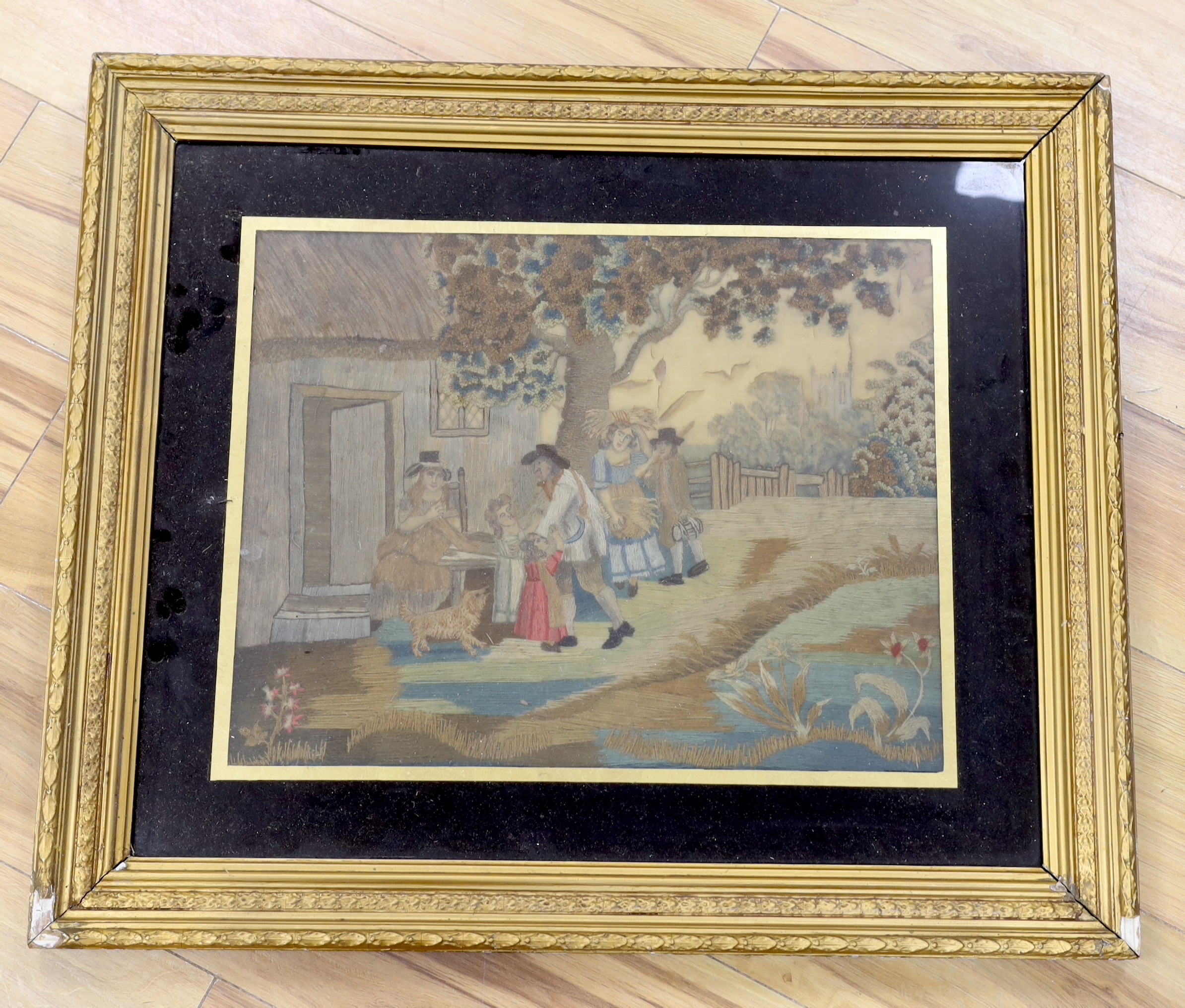An early 19th century embroidery on silk of figures before a cottage, 47 x 37cm